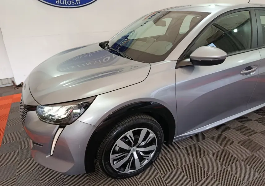 Vue 3/4 avant droit d'une Peugeot 208 électrique Active Business gris clair avec phares LED et jantes stylisées.