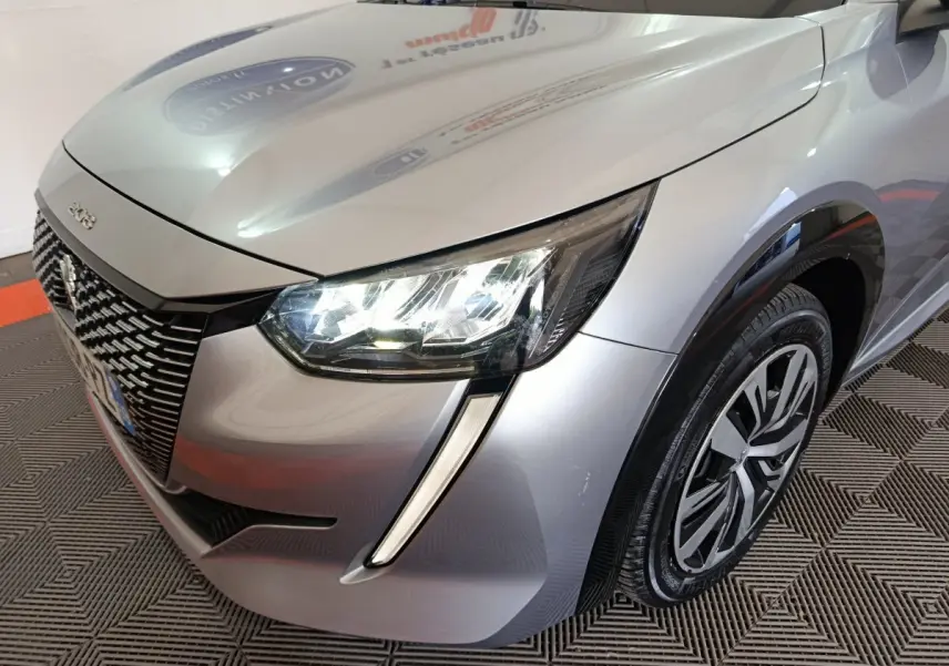 Vue 3/4 avant droit d'une Peugeot 208 électrique gris clair avec feux LED et jante spécifique Active Business.