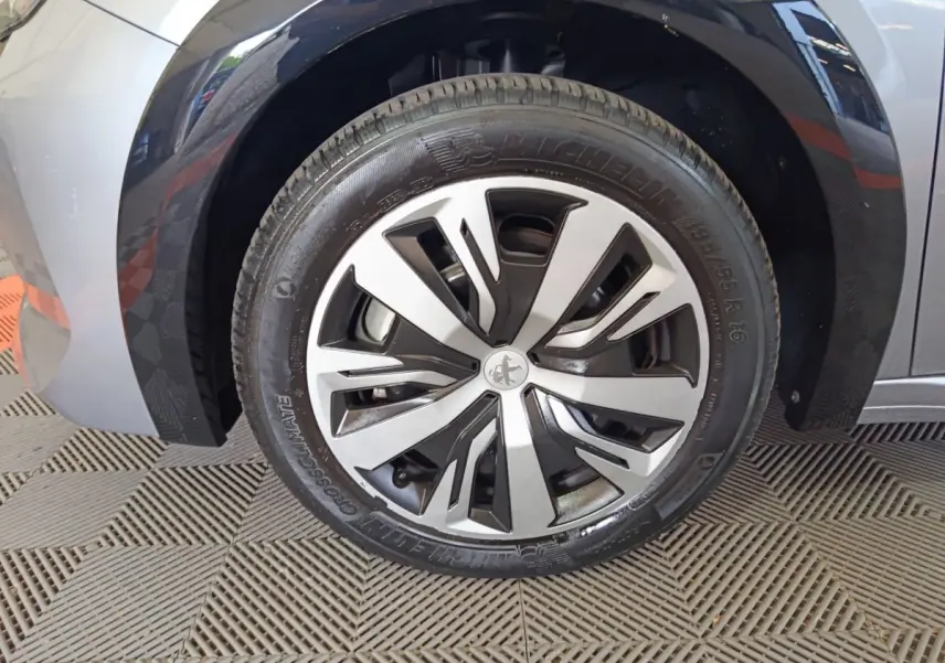 Gros plan sur la roue avant gauche gris clair d'une Peugeot 208 Electrique Active Business avec jante design Peugeot.