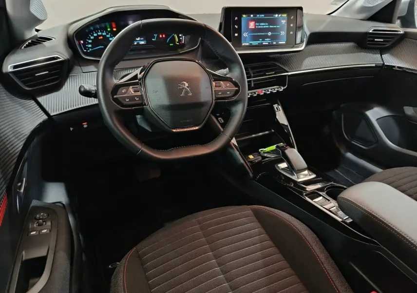 Intérieur de la Peugeot 208 électrique 2020, vue du poste de conduite avec volant cuir et écran tactile central.