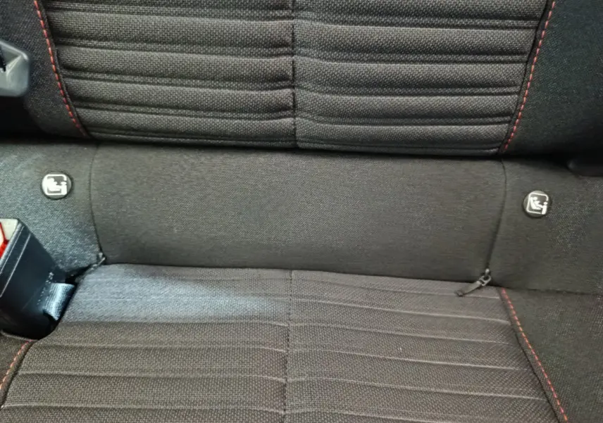 Gros plan sur la banquette arrière noire avec surpiqûres rouges et fixations Isofix du Peugeot 208 Electrique Active Business.