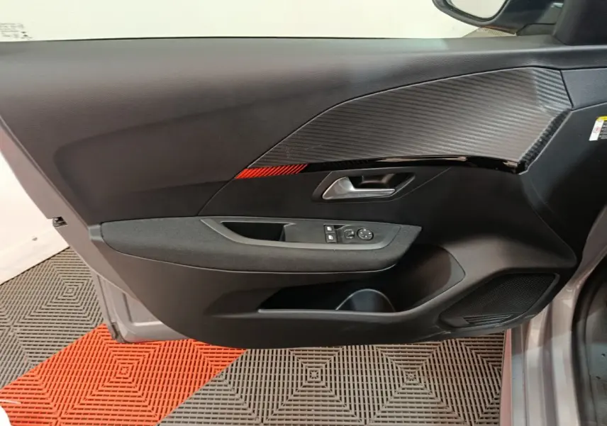 Vue intérieure côté gauche de la porte d'une Peugeot 208 électrique gris clair avec insert décoratif noir et rouge.