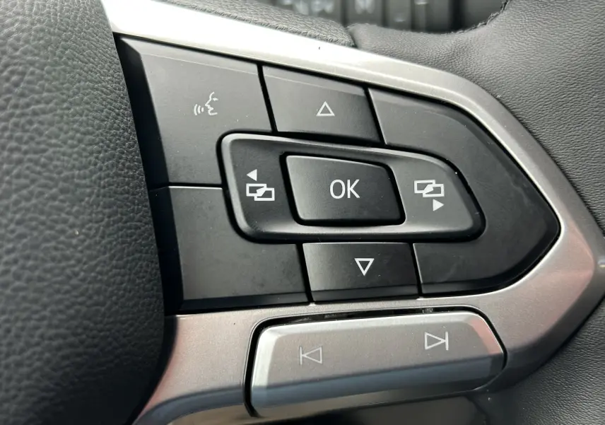 Gros plan sur les commandes multifonctions noires et argentées du volant du Volkswagen Transporter T7 ProCab 2026.