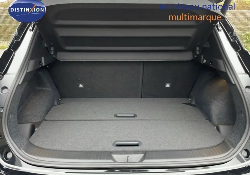 Coffre ouvert vu de l’arrière d’un Nissan Qashqai noir perle métal avec banquette rabattue et espace de chargement plat.