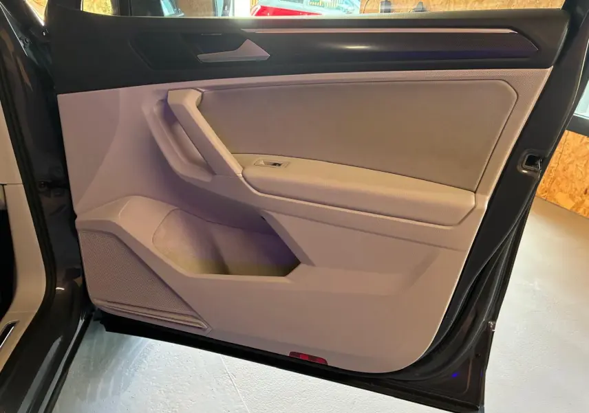 Vue intérieure de la porte avant droite du Volkswagen Tiguan 2023 gris, avec garniture beige et poignée intégrée.