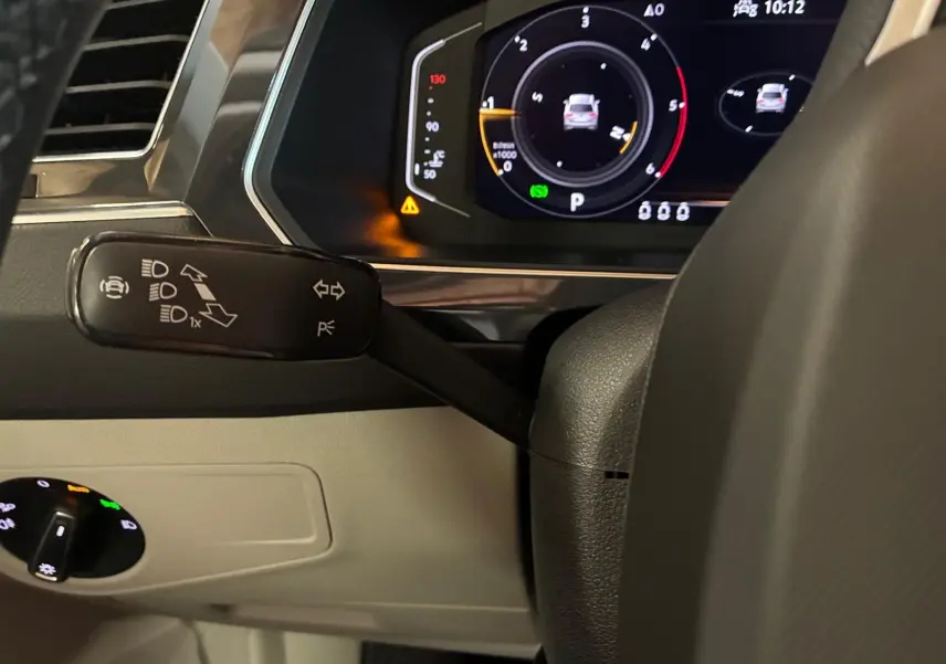 Gros plan sur le combiné d'instruments digital et la commande de clignotants du Volkswagen Tiguan 2023, intérieur noir et beige.