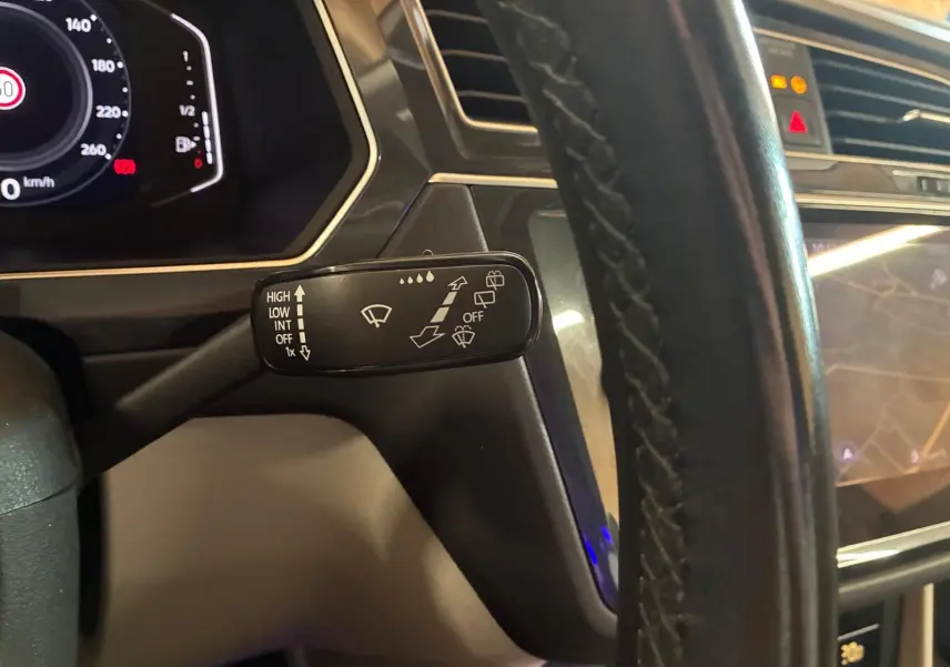 Gros plan sur la commande d’essuie-glace à gauche du volant dans l’habitacle du Volkswagen Tiguan gris 2023.