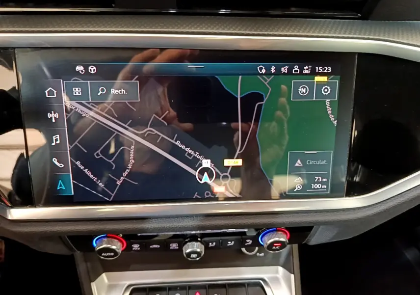 Vue rapprochée de l’écran tactile central du tableau de bord de l’Audi Q3 noir, affichant la navigation GPS.