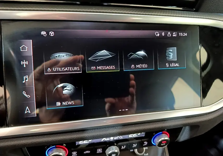 Écran tactile central de l'Audi Q3 35 TDI 2021 affichant le menu principal avec commandes climatisation en dessous.