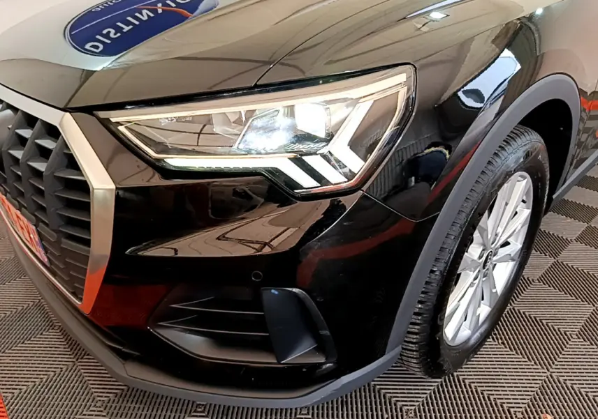 Gros plan sur l'avant droit noir d'un Audi Q3 35 TDI 150 S tronic avec phare LED et jante argentée.