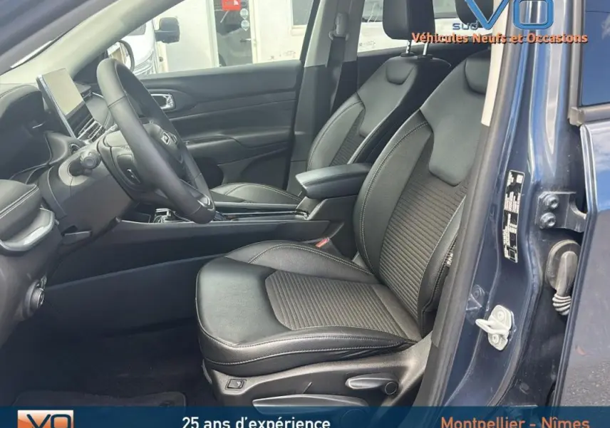 Vue intérieure côté conducteur du Jeep Compass bleu 2023, montrant sièges en cuir noir et accoudoir central.