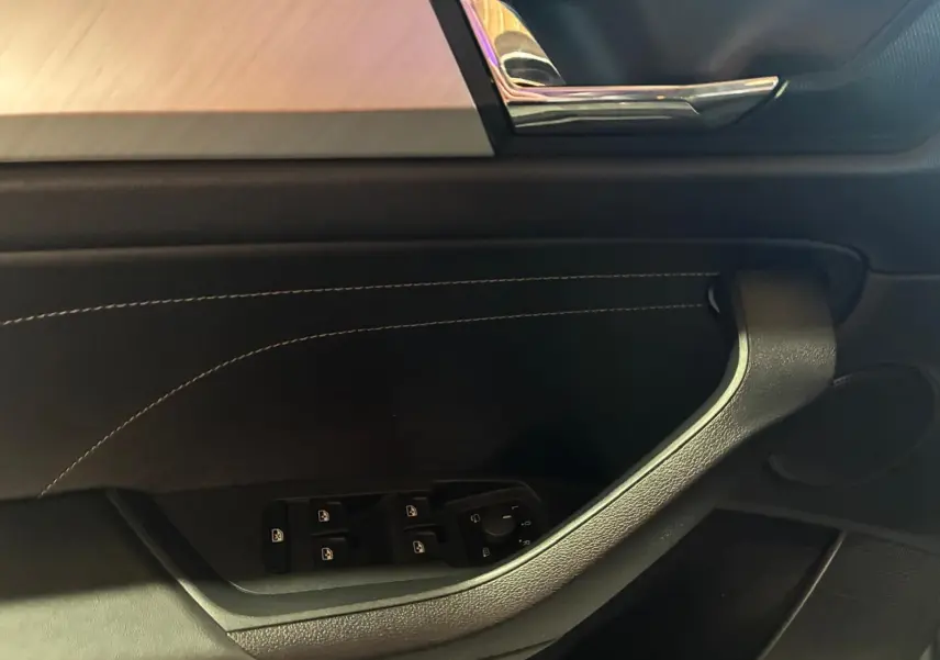Détail de la porte intérieure côté conducteur du Skoda Kodiaq gris, avec commandes électriques et insert chromé.