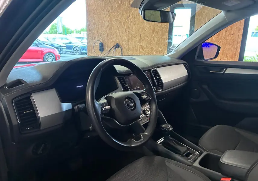Vue intérieure côté conducteur du Skoda Kodiaq gris 2023, avec tableau de bord moderne et volant cuir noir.