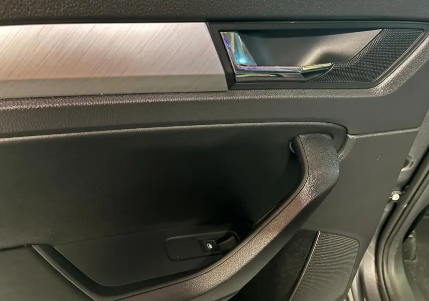Gros plan sur la porte intérieure côté gauche du Skoda Kodiaq 2023, avec insert aluminium brossé et poignée chromée.