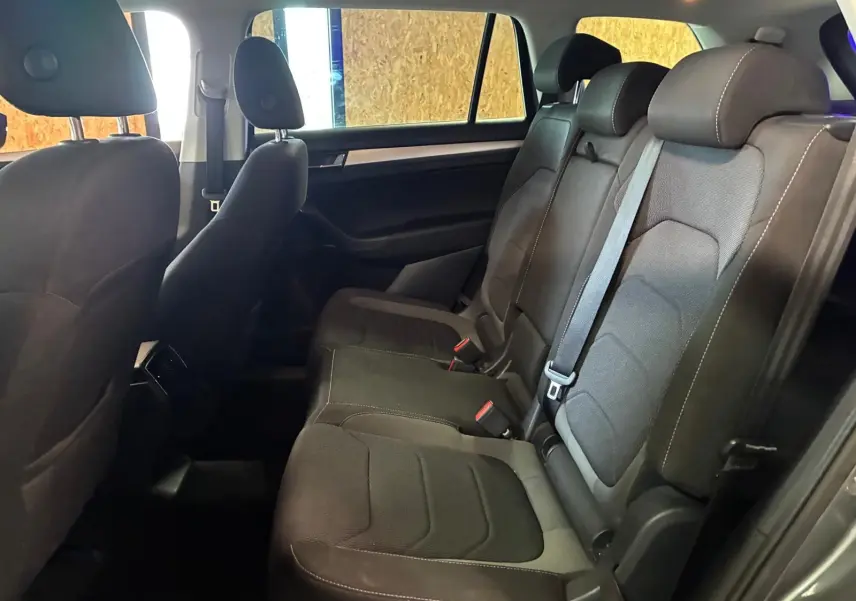 Vue latérale intérieure des sièges arrière gris foncé du Skoda Kodiaq 7 places avec ceintures et appuie-têtes visibles.