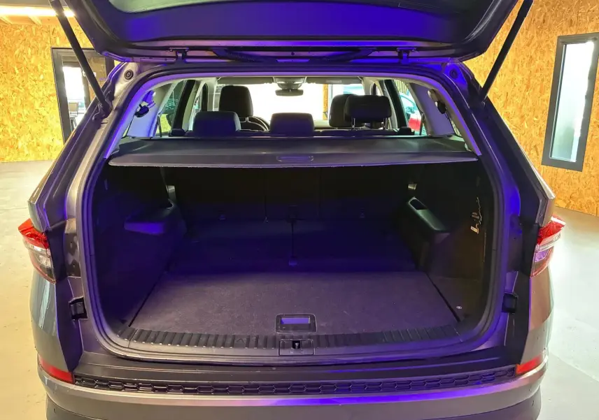 Coffre ouvert vu de l'arrière d'un Skoda Kodiaq gris, montrant l'espace de chargement et la tablette cache-bagages.