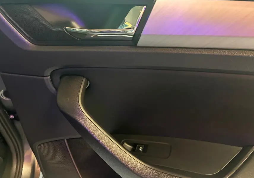 Gros plan sur la poignée intérieure côté gauche de la porte d’un Skoda Kodiaq gris avec insert décoratif aluminium.