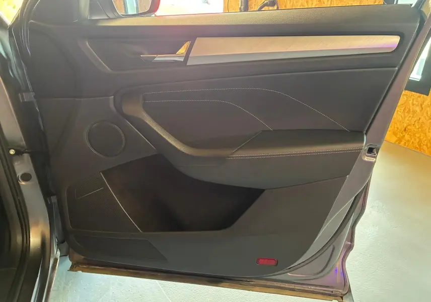 Vue intérieure côté gauche de la porte arrière grise du Skoda Kodiaq 2023 avec insert aluminium brossé et haut-parleur intégré.