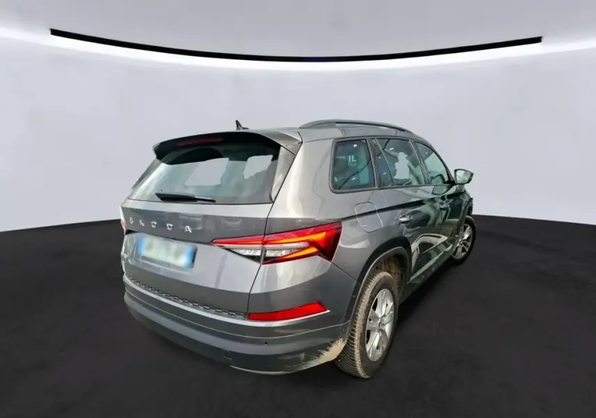 Vue 3/4 avant d'un Skoda Kodiaq gris métallisé avec jantes alu 17'' dans un showroom intérieur.