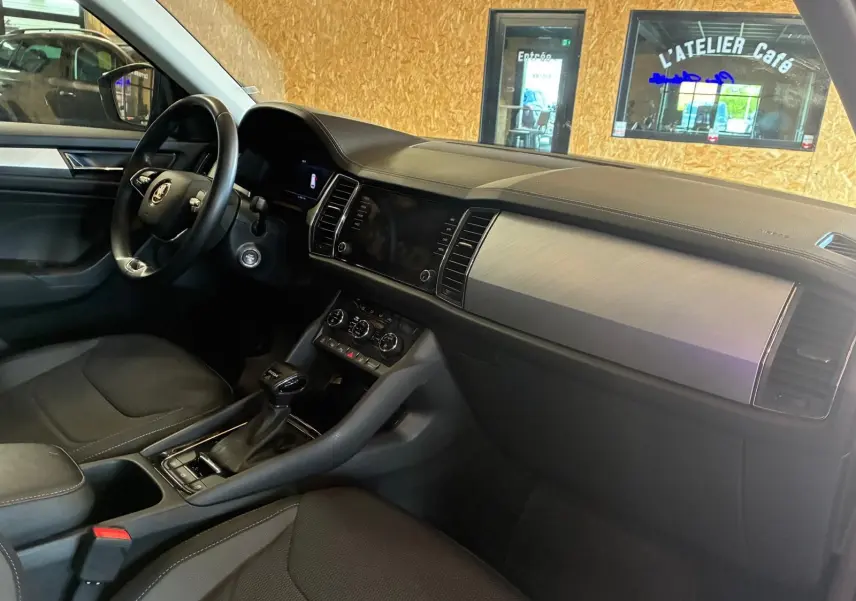 Vue intérieure côté conducteur du Skoda Kodiaq gris 2023, tableau de bord avec inserts aluminium et console centrale noire.
