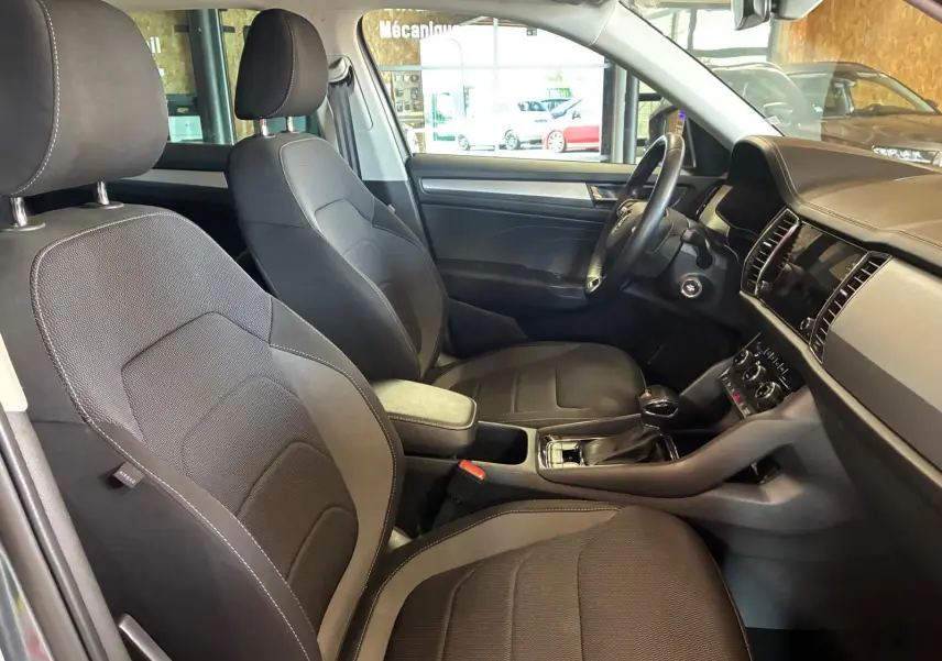 Vue intérieure côté droit du Skoda Kodiaq 2023, montrant les sièges tissu noirs et la console centrale avec levier de vitesses.