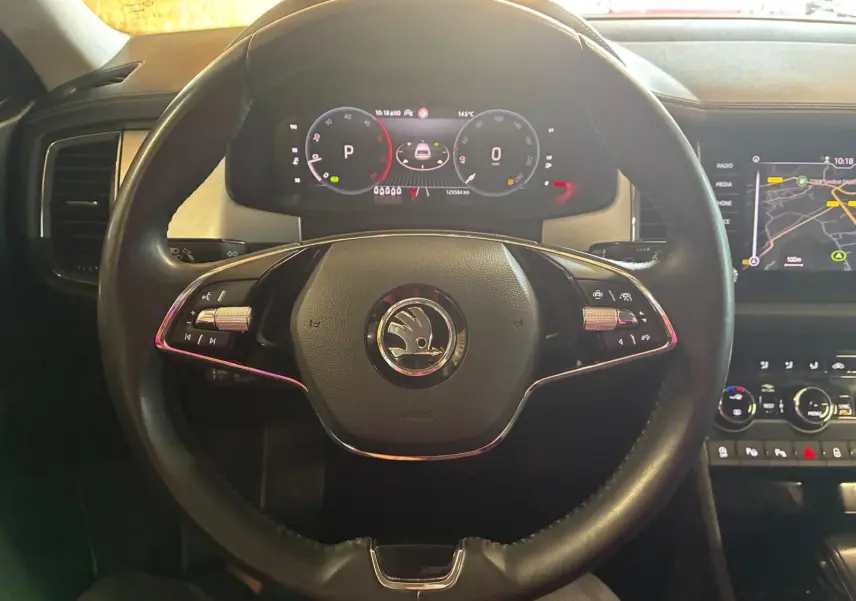 Vue rapprochée du volant noir et du tableau de bord digital du Skoda Kodiaq 2023 avec écran GPS allumé.