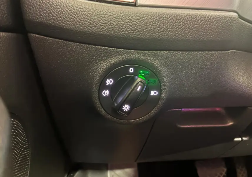 Gros plan sur le bouton de commande des phares du Skoda Kodiaq gris, avec indicateurs lumineux verts activés.