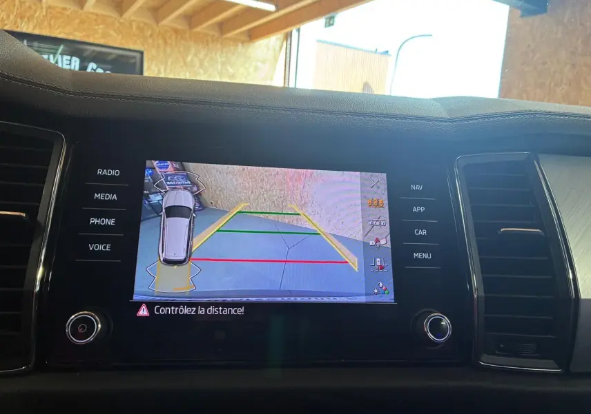 Écran central du tableau de bord montrant la caméra de recul et l’aide au stationnement du Skoda Kodiaq gris.