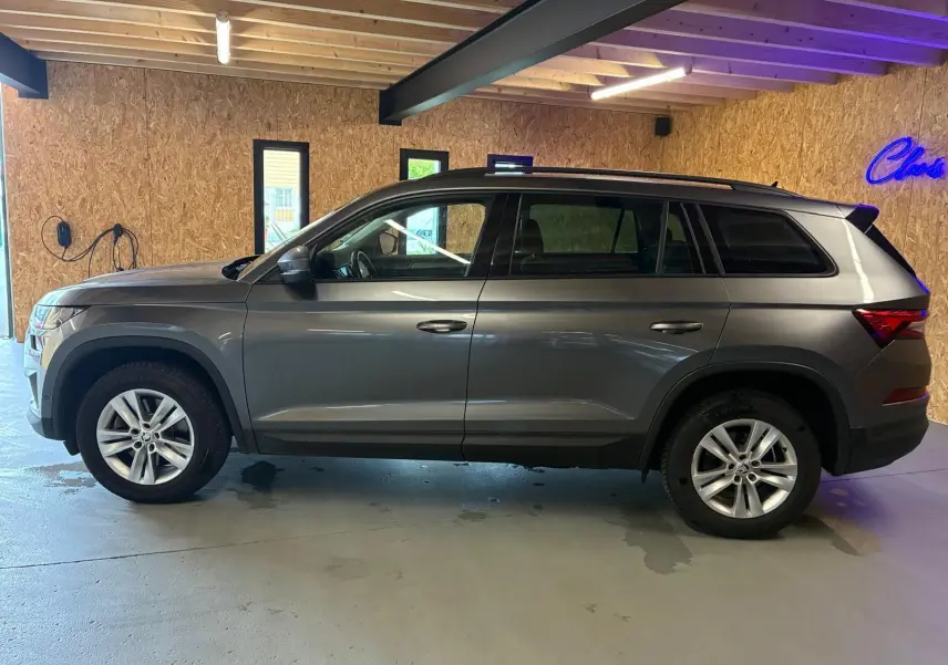 Vue de profil côté gauche d'un Skoda Kodiaq gris 2023 avec jantes alu 17 pouces dans un garage.