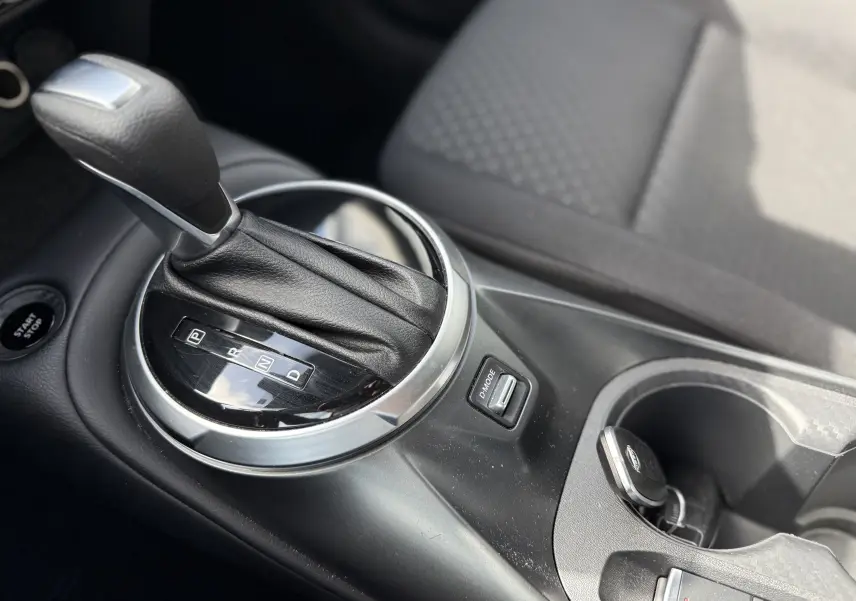 Gros plan sur la console centrale du Nissan Juke Hybrid 2025, montrant le levier de vitesse automatique et le bouton D-Mode.