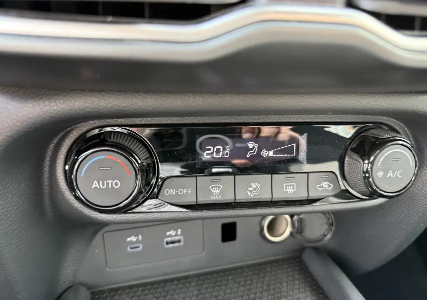 Gros plan sur la console de climatisation automatique du Nissan Juke Hybrid 2025, avec affichage digital à 20°C.
