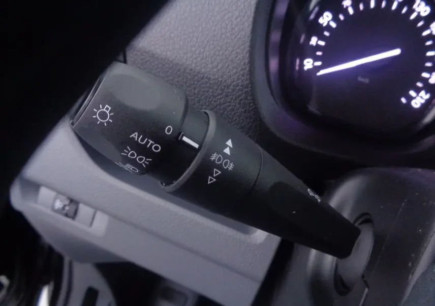 Gros plan sur la commande des phares du Peugeot Expert Fourgon noir métal, avec tableau de bord partiellement visible.