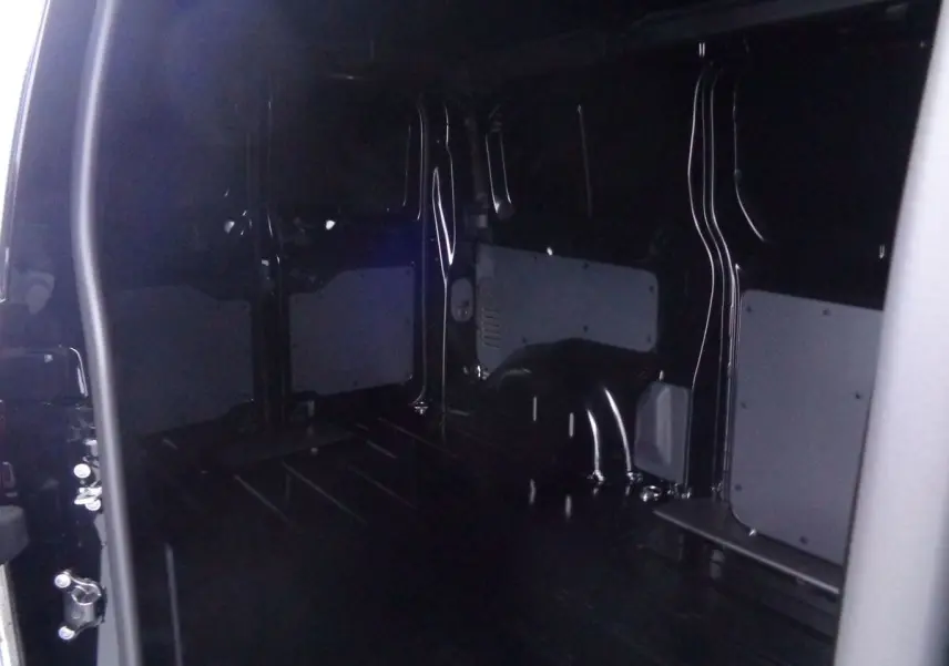 Intérieur du fourgon Peugeot Expert Standard noir métal, vue depuis la porte latérale ouverte montrant l'espace de chargement vide.