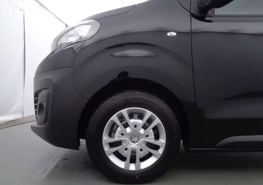 Vue latérale côté avant gauche du Peugeot Expert Fourgon noir métal, mettant en valeur la roue et l'aile avant.