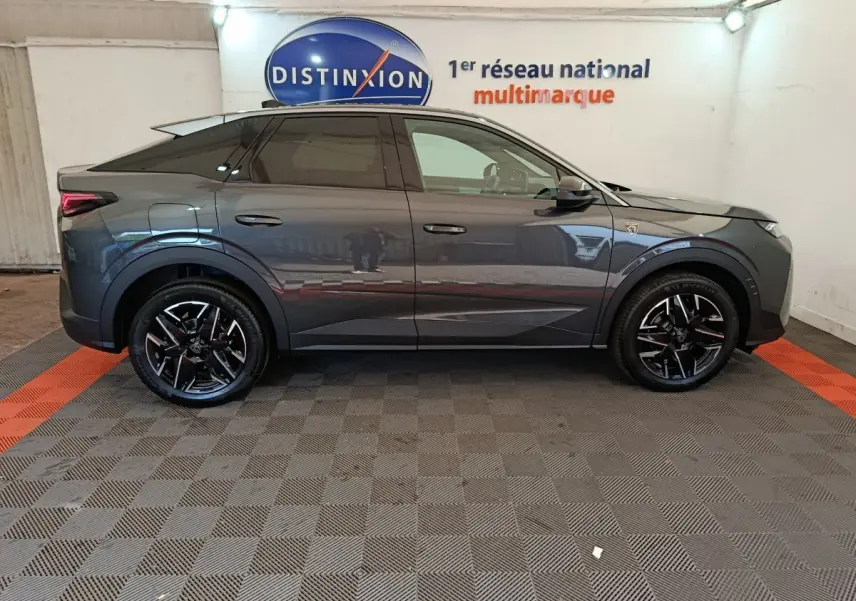 Profil droit du Peugeot 3008 gris foncé 1.2 HYBRID 145 GT en intérieur avec jantes noires et logo distinctif sur aile avant.