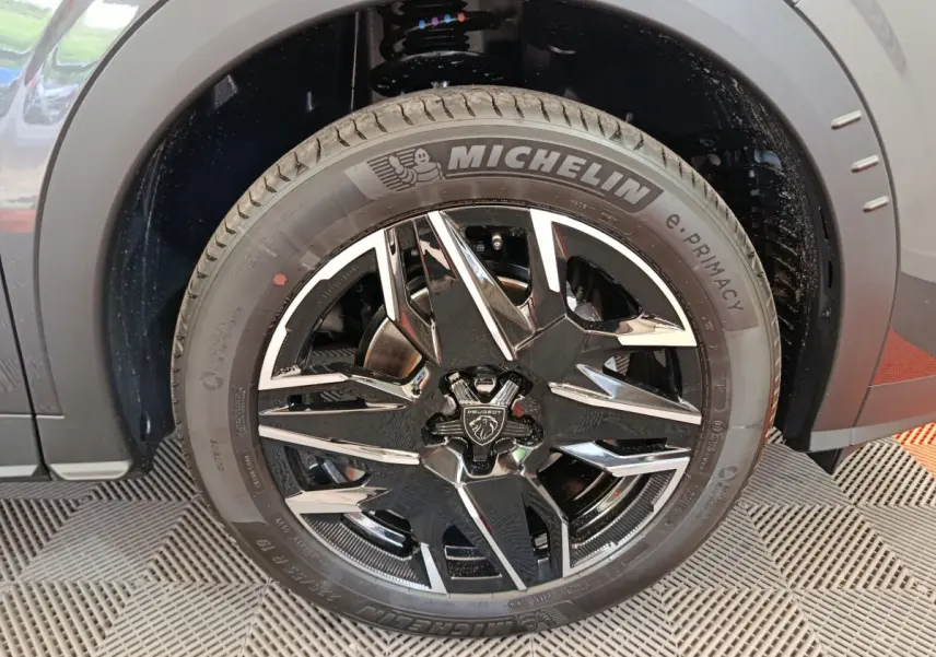 Gros plan sur la roue avant gauche gris foncé du Peugeot 3008 1.2 Hybrid 145 GT avec jante noire et détails chromés.
