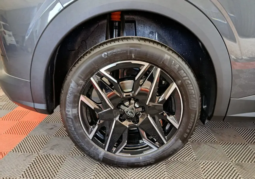 Gros plan sur la roue avant droite du Peugeot 3008 gris foncé, jante alliage noire et détails Michelin visibles.
