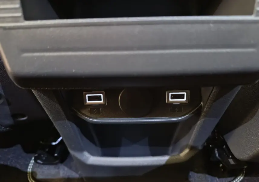 Prise USB double arrière noire du Peugeot 3008 gris foncé, version hybride 2025, vue centrée en intérieur.
