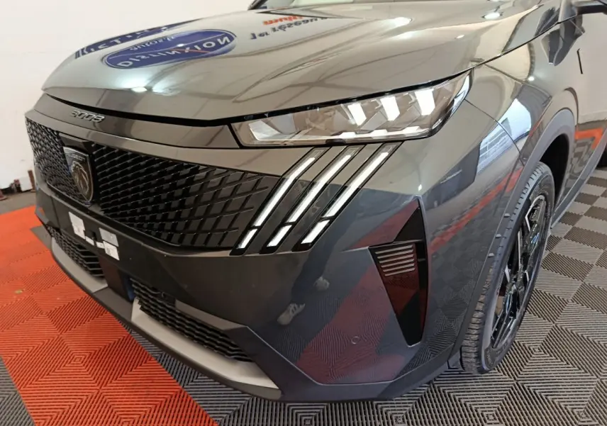 Vue 3/4 avant droit du Peugeot 3008 gris foncé mettant en valeur ses phares LED et sa calandre distinctive.