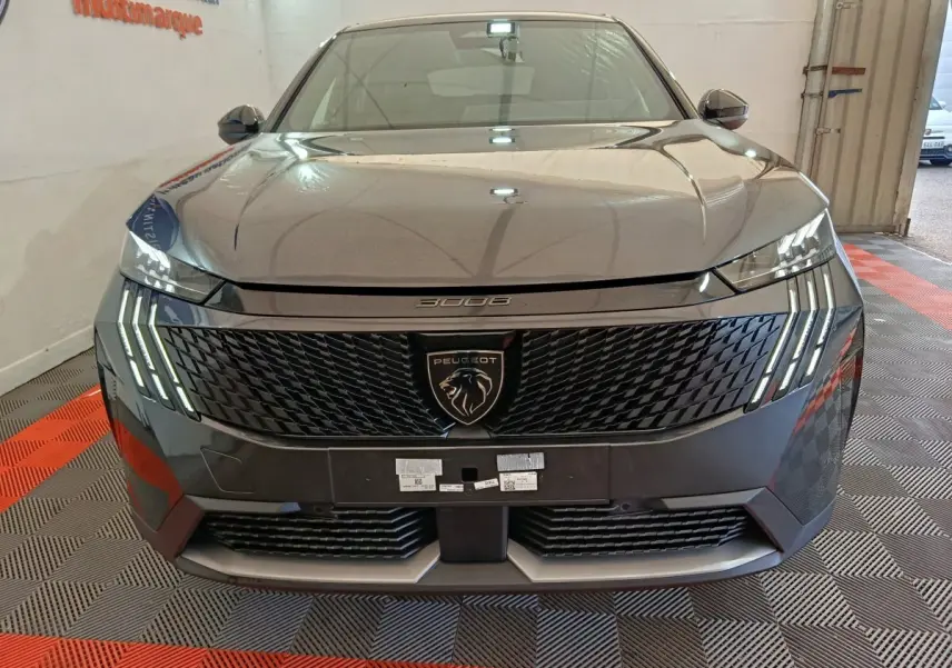 Vue frontale du Peugeot 3008 gris foncé 2025 avec calandre noire et feux LED à griffes distinctifs allumés.