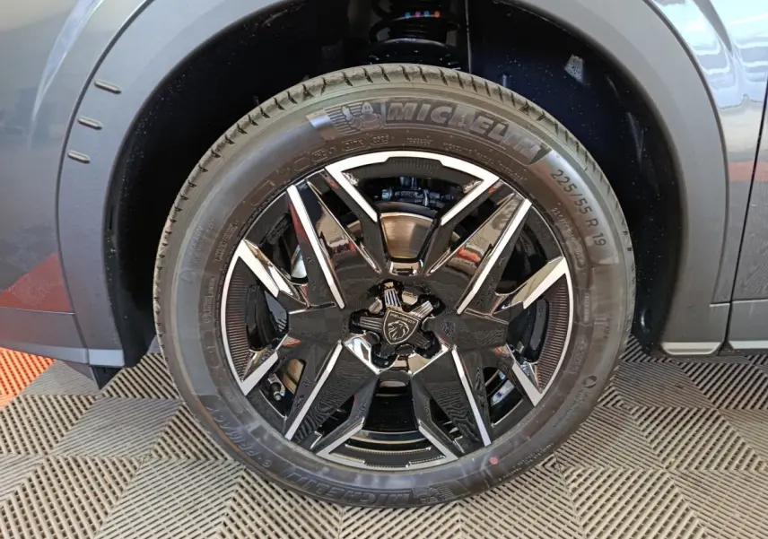 Gros plan sur la roue avant gauche du Peugeot 3008 gris foncé avec jante noire et détails chromés.