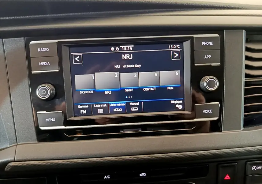 Écran tactile central du tableau de bord du Volkswagen Transporter blanc, affichant la radio NRJ en mode FM.