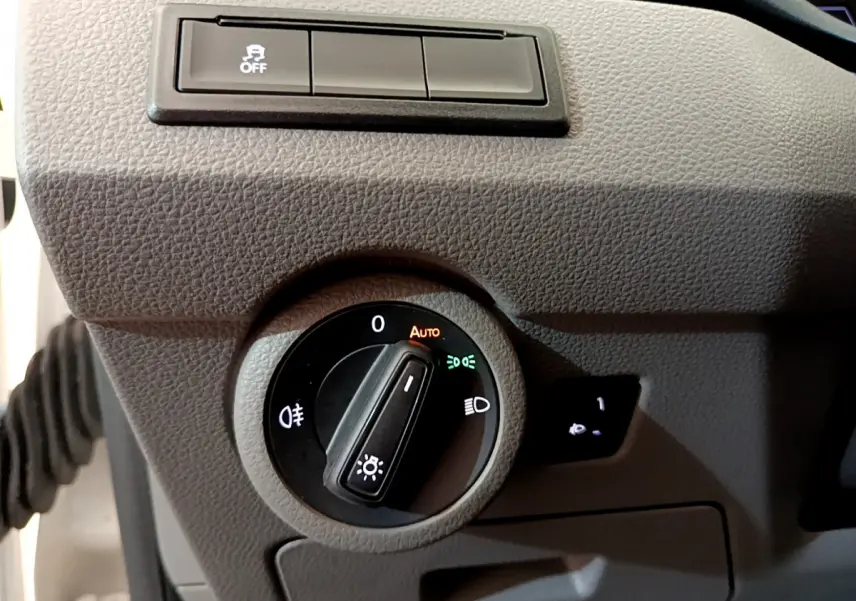 Gros plan sur la commande des phares du Volkswagen Transporter 2.0 TDi blanc, avec réglage automatique et antibrouillard.