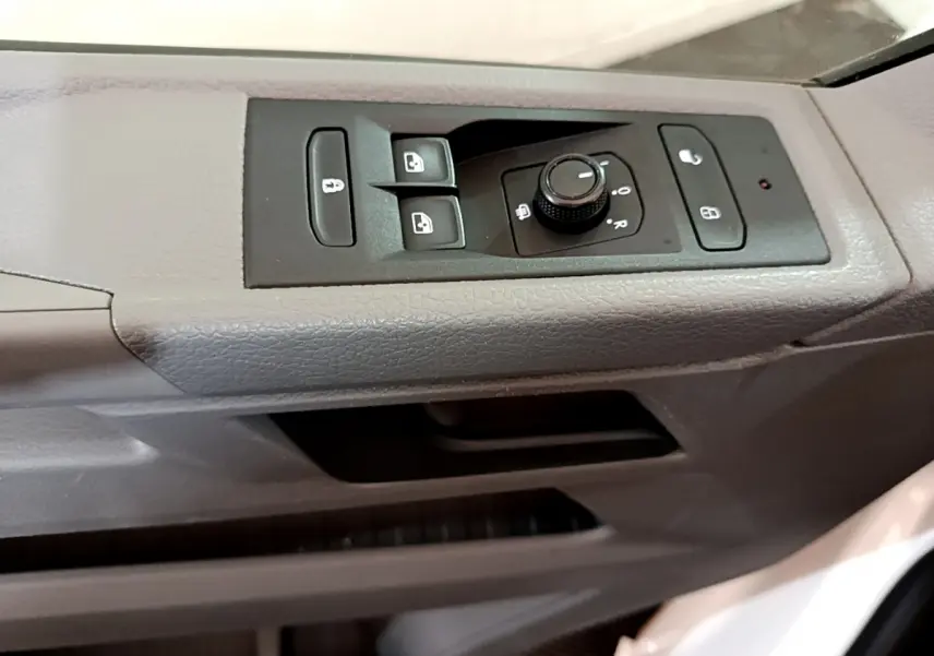 Détail des commandes de lève-vitres et réglage des rétroviseurs sur la porte côté conducteur du Volkswagen Transporter blanc.