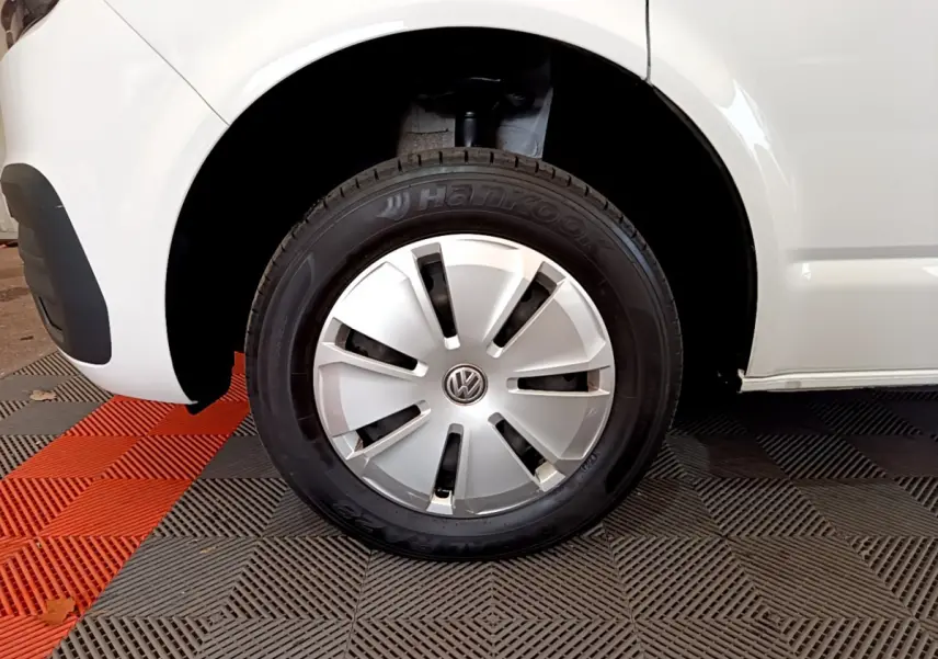 Gros plan sur la roue avant gauche blanche d’un Volkswagen Transporter 2.0 TDi 150 DSG7 avec enjoliveur argenté.