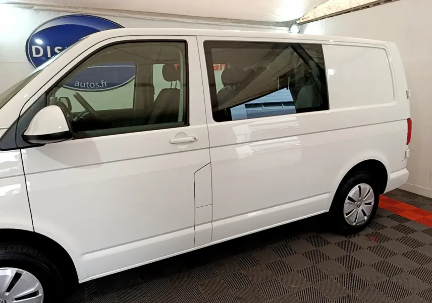 Vue de profil côté gauche du Volkswagen Transporter blanc 2.0 TDi avec vitres teintées et jantes acier.