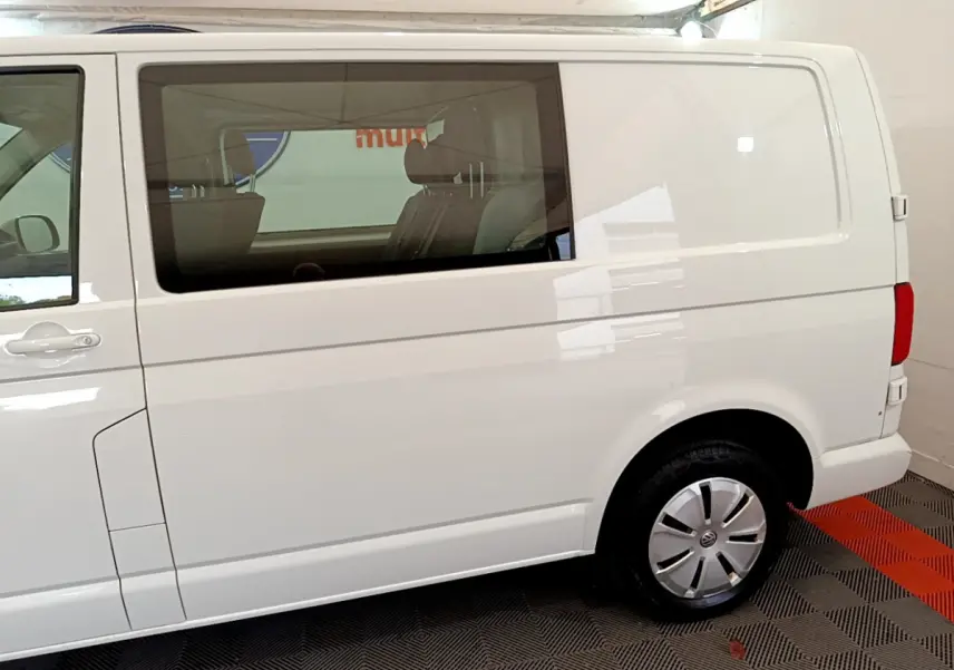 Vue latérale droite d'un Volkswagen Transporter blanc 2.0 TDi 150 DSG7 avec vitre arrière teintée et jante acier.