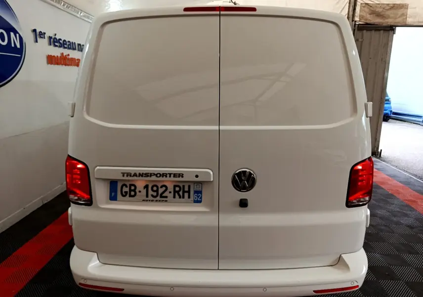Vue arrière d'un Volkswagen Transporter blanc 2021 avec portes battantes et feux rouges allumés en intérieur.