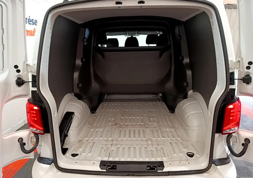 Vue arrière du Volkswagen Transporter blanc 2021 avec portes ouvertes montrant l'espace de chargement vide et la cloison pleine vitrée.