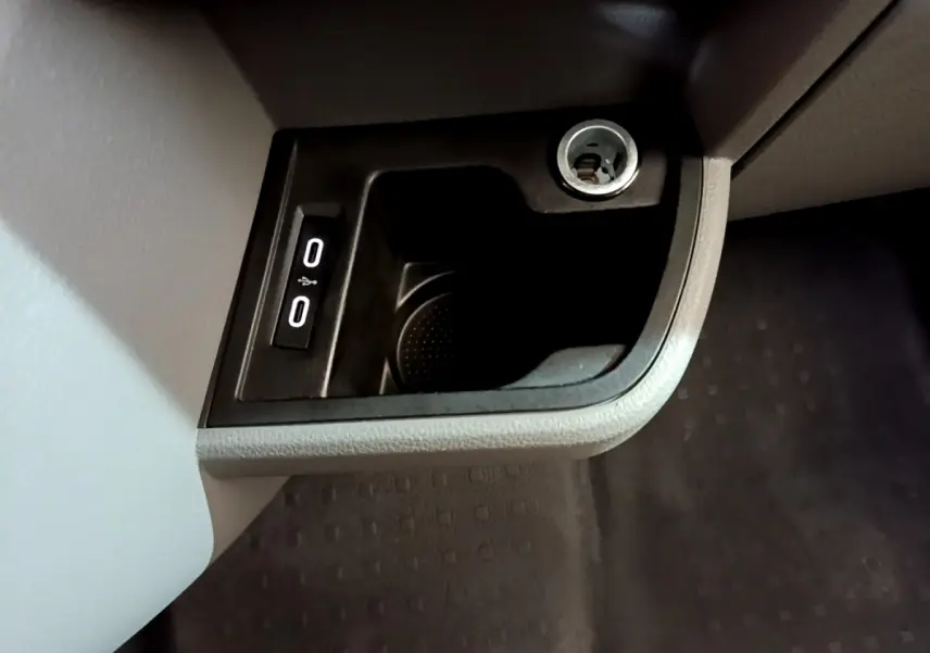 Gros plan sur la prise 12V et ports USB intégrés dans la console intérieure du Volkswagen Transporter blanc.